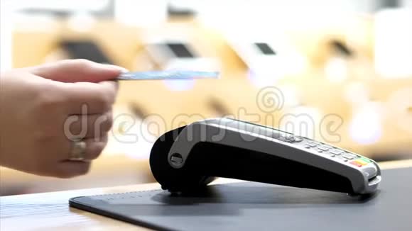 在银行终端上用NFC芯片通过塑料卡进行女性手工支付的特写视频的预览图