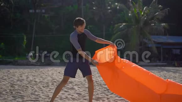 一个年轻人在热带海滩上的超慢镜头使充气沙发充气暑假概念视频的预览图