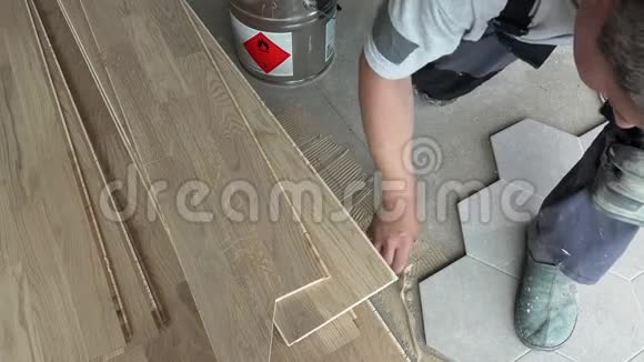 用刮刀的人在靠近六角形瓷砖的地板上涂胶视频的预览图
