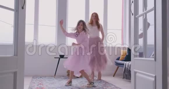 活跃的年轻妈妈保姆和可爱的小女儿在现代家庭客厅跳舞幸福的家庭母亲视频的预览图