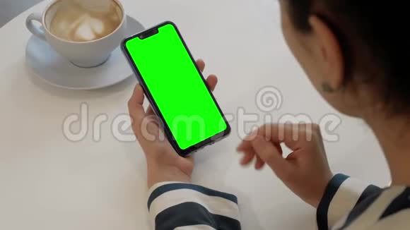 一个女人正在和一个朋友通过绿色屏幕智能手机的视频通话视频的预览图