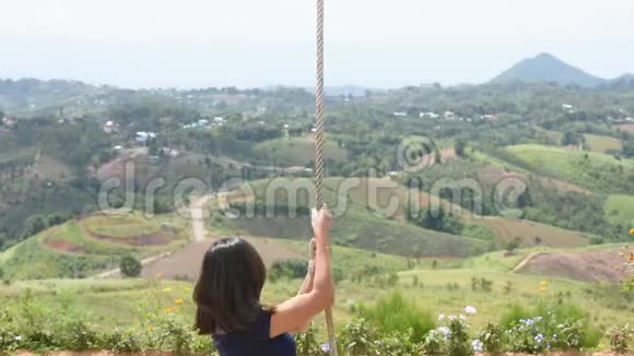 拉着绳子的女人摇着秋千椅快乐地玩耍背景山在泰国的霍霍风电场里视频的预览图