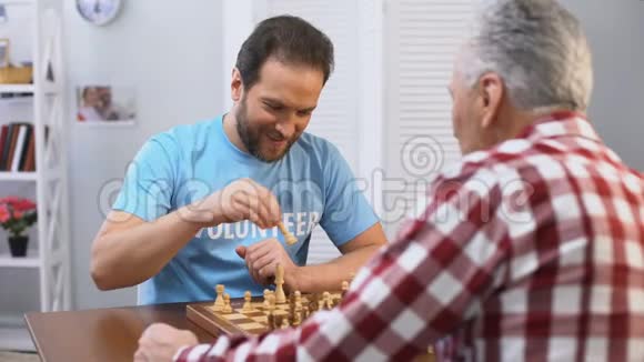 中年男性志愿者在养老院和老人下棋爱好视频的预览图