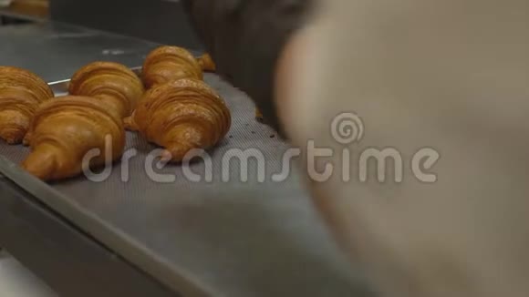 一个糖果师把刚出炉的糕点倒出来托盘里放着一块金黄色的面包皮牛角面包视频的预览图