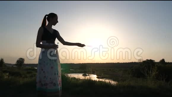 穿裙子的女人在日落时缓慢地做肥皂泡视频的预览图