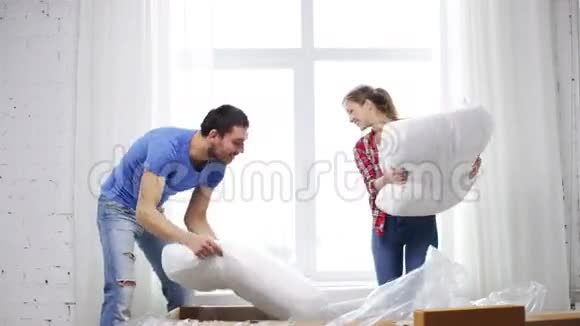 微笑的夫妇打开一个大纸板箱和沙发视频的预览图