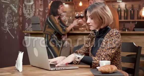 年轻的商务女性在咖啡店里用笔记本电脑输入一条重要信息视频的预览图