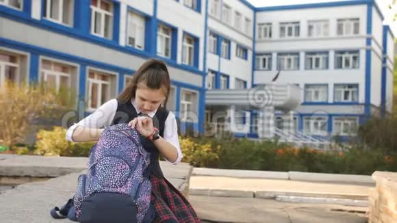 妈妈走过去亲吻学院附近的少女学生女孩坐在学院的院子里视频的预览图