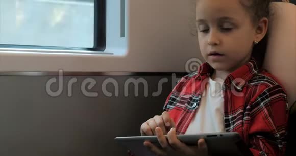 可爱的小女孩用平板电脑娱乐儿童休闲时间乘坐火车玩手机游戏视频的预览图