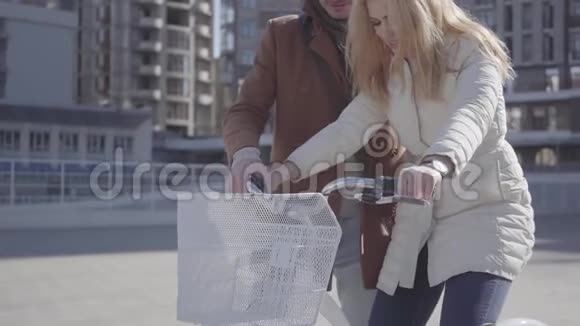 穿着棕色外套的帅哥在城市里教他的女朋友骑自行车一对美丽的城市视频的预览图