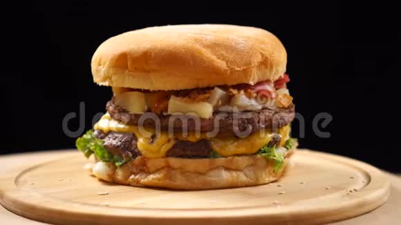 汉堡有牛肉奶酪和蔬菜在木板上旋转黑色背景视频的预览图