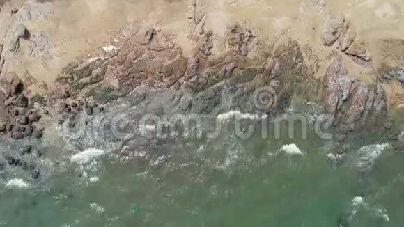 从空中俯瞰海滩上的热带岩石海浪把它拉回视频的预览图