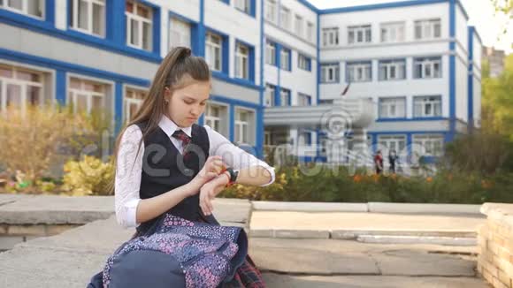 在学院的院子里休息的少女拿着一个背包坐在女儿墙上并把闹钟按在上面视频的预览图