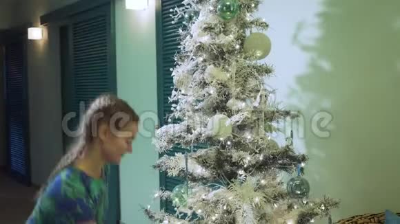 年轻女子穿着五颜六色的衣服装饰圣诞树视频的预览图