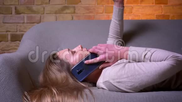 特写侧景照片年轻迷人的白种人黑发女性有一个电话躺在沙发上悠闲地躺着视频的预览图