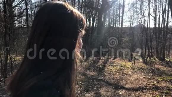 户外画像年轻美丽的白种人少女微笑着看着镜头森林之路在一个刮风的日子视频的预览图