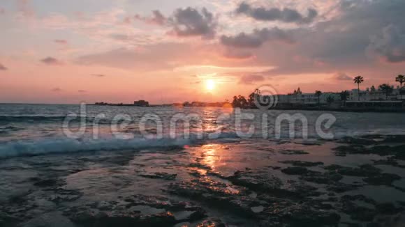 日落时的海浪日落时的海沫日落时美丽的粉红色天空粉红色的云海滩日落码头日落日落时分视频的预览图