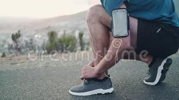 一名年轻的白人男子在跑步前把鞋系好站起来看风景视频的预览图