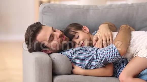 快乐的父亲躺在沙发上拥抱孩子拥抱在一起视频的预览图