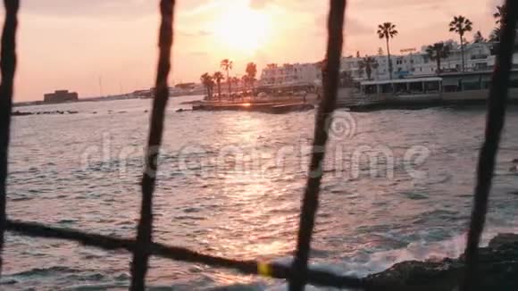 日落穿过格子粉红色的夕阳穿过篱笆美丽的海上日落码头上的粉红色日落日落时的旅游长廊粉色视频的预览图