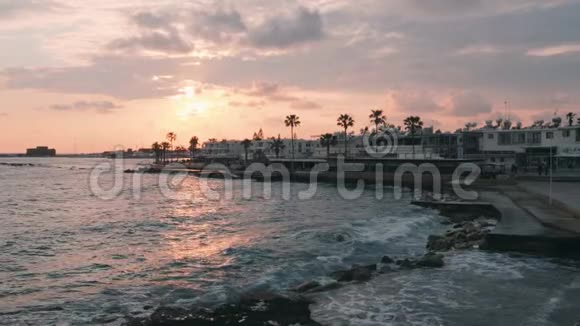 码头的粉色日落日落时美丽的行人区带棕榈的旅游长廊巨大的海浪在太阳下撞击码头视频的预览图