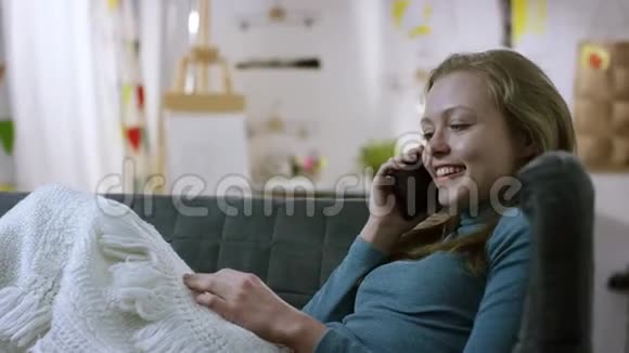 年轻女子在沙发上用手机说话视频的预览图