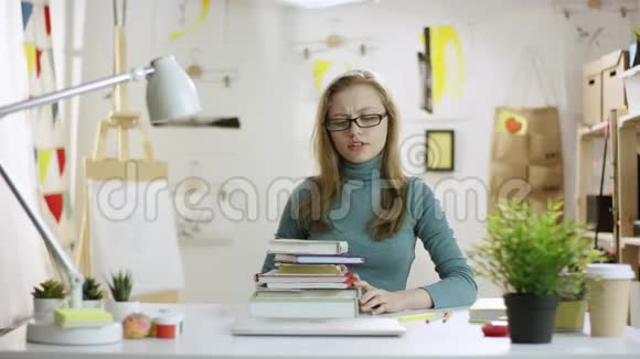 年轻漂亮的女人把书扔出桌子打开笔记本电脑上网视频的预览图