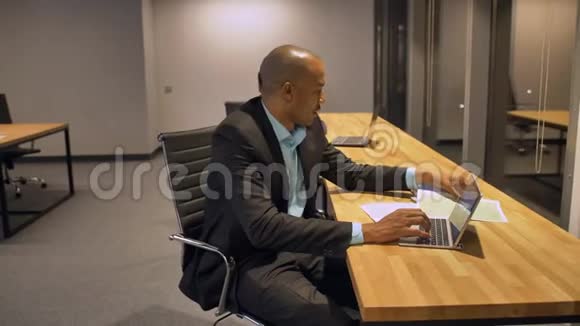 非洲商人和他的同事深夜在办公室里用笔记本电脑工作视频的预览图
