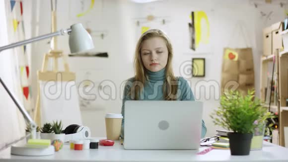 年轻女子在手提电脑上网时用手机聊天视频的预览图