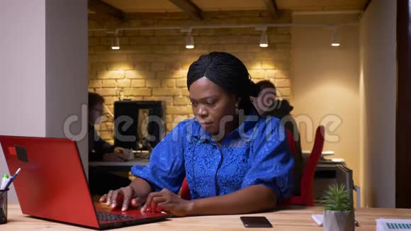 美国黑人女商人使用笔记本电脑在电话中查看通知并正在进行特写拍摄视频的预览图