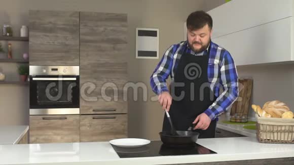留胡子的男人用平底锅在厨房里炸薯条用盘子里的紫罗兰慢吞吞的视频的预览图