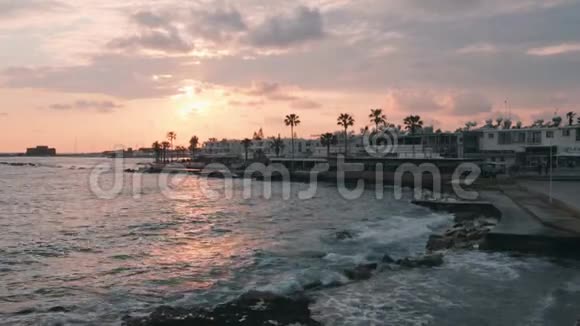 码头的粉色日落日落时美丽的行人区带棕榈的旅游长廊巨大的海浪在太阳下撞击码头视频的预览图
