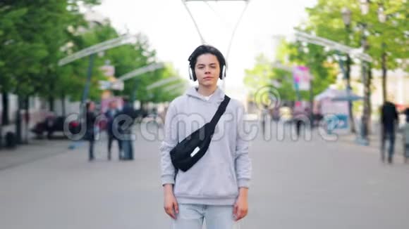 戴耳机的青少年站在户外街头的延时画像视频的预览图