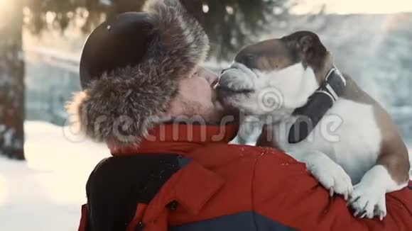 在冬天阳光明媚的日子里大胡子的男人拥抱着他的斗牛犬友谊圣诞节冬天宠物的概念视频的预览图