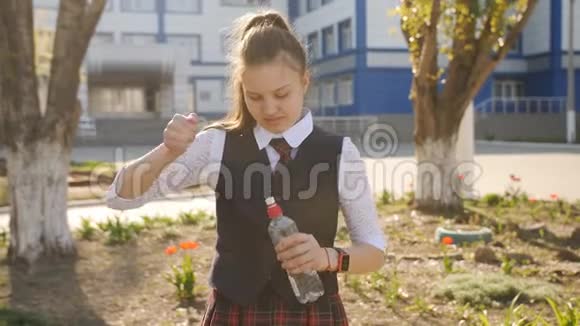 穿校服的女学生从学校附近的塑料瓶里喝水视频的预览图