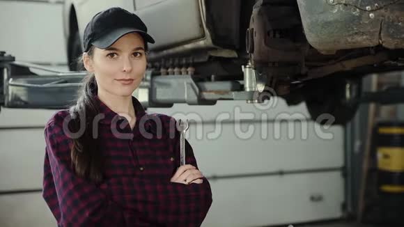 一个漂亮女孩的肖像一个汽车修理工手里拿着一把扳手放在电梯上的背景上视频的预览图