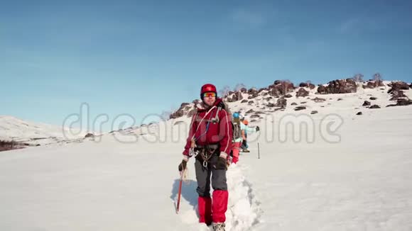 登山者站着威严地看着他的团队走过的道路他身后站着他友好的球队和白雪视频的预览图