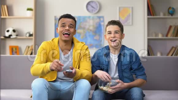非裔美国人和白人朋友在电视上看喜剧节目吃爆米花视频的预览图