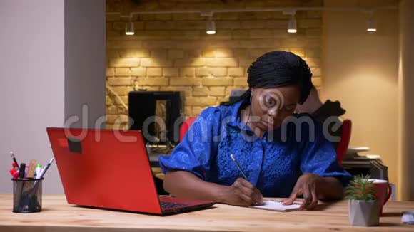 成年非裔美国女商人在办公室室内打字和做笔记的特写镜头视频的预览图