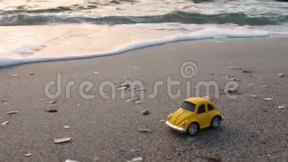 假期和旅游理念鲜艳的小复古玩具车上的沙子在背景下波涛汹涌的大海视频的预览图