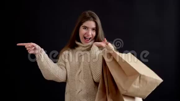 穿着针织毛衣的白种人女孩手里拿着一堆礼品袋手指放在一边视频的预览图