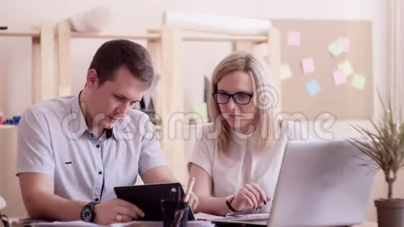 那个男人和办公室里的女孩坐在同一张桌子上对她的辛勤工作解释说她正坐在眼镜里视频的预览图
