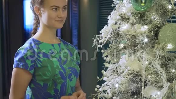 年轻女子穿着五颜六色的衣服装饰圣诞树视频的预览图