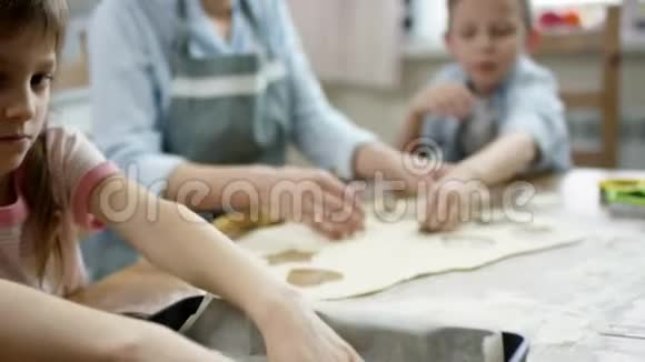 妈妈一边给孩子们讲故事一边铺床单一边在厨房的桌子上擀面包做饼干视频的预览图