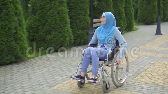 戴眼镜戴传统围巾坐轮椅的阿拉伯青年妇女视频的预览图