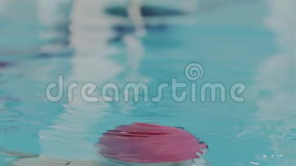 慢动作的超级宏观画像戴着红游泳帽的年轻职业游泳运动员的脸从水中浮现视频的预览图