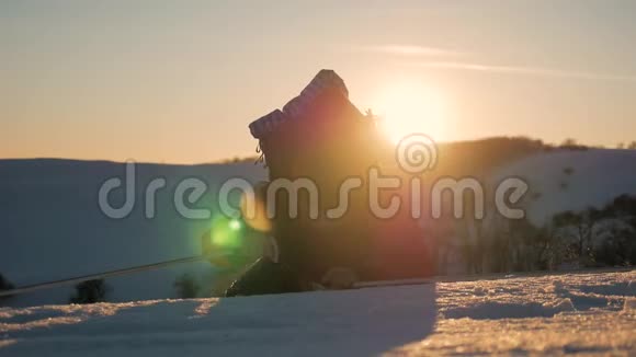 登山者到达雪山的顶端一个背着背包的登山者爬上了雪坡日落的天空视频的预览图