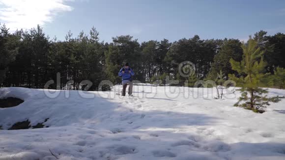 冒险男子徒步旅行者穿着温暖的衣服和背包走在雪覆盖的道路上松林一个人走过视频的预览图