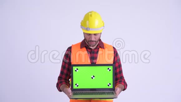 快乐的波斯人建筑工人一边说一边展示笔记本电脑视频的预览图