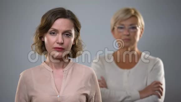 伤心的年轻女子在镜头前看着严老母亲站在后面问题视频的预览图